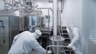 Mitarbeiter eines Pharmaunternehmens arbeiten in einem Reinraum an einer Gelmischanlage. (Foto: Hendrik Schmidt/dpa-Zentralbild/dpa)