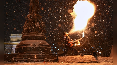 Heiß und kalt: Ein Straßenkünstler führt bei Schneefall eine Feuershow im russischen St. Petersburg auf. (Foto: Dmitri Lovetsky/AP/dpa)