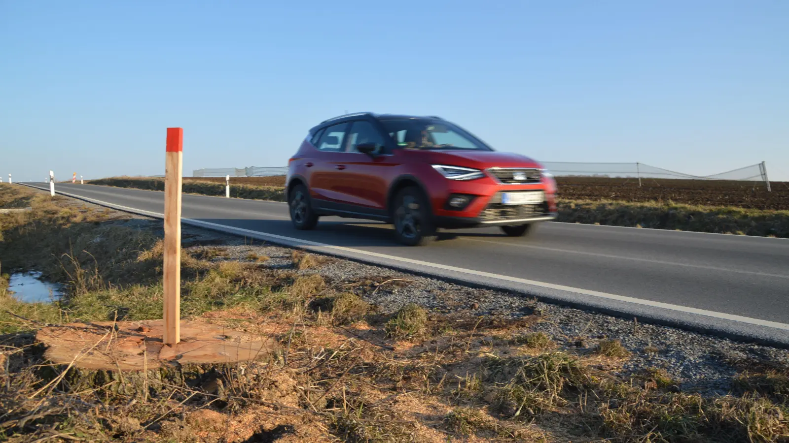 An der Staatsstraße zwischen Uffenheim und Adelhofen brausen die Autos nun am Baumstumpf vorbei. Dieser und der rote Pflock erinnern noch an das Politikum. (Foto: Johannes Zimmermann)