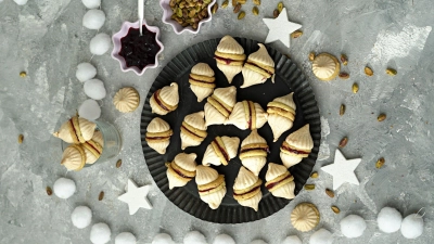 Durch die Geleefüllung werden zwei Vanillekipferl miteinander verbunden. Dann bekommt der Doppel-Keks auch noch zwei Zipfelmützchen in Form von Baiserhauben. (Foto: Mareike Pucka/biskuitwerkstatt.de/dpa-tmn)