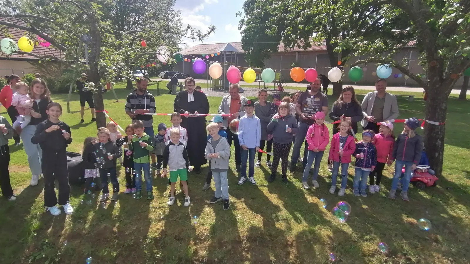 Das Band wird durchtrennt: Mit den Kindern freuten sich (von links) Jugendbeauftragter Herbert Rosenbauer, Pfarrer Christian Dellert, zweiter Bürgermeister Werner Schmitz, Stefanie Poledne (Projekt-Team), Michael Strauß (Vorsitzender der FFW Irsingen), Stefanie Strauß (Projekt-Team) und Markus Kober (Vorstand der VR-Bank im südlichen Franken). (Foto: Friedrich Zinnecker)