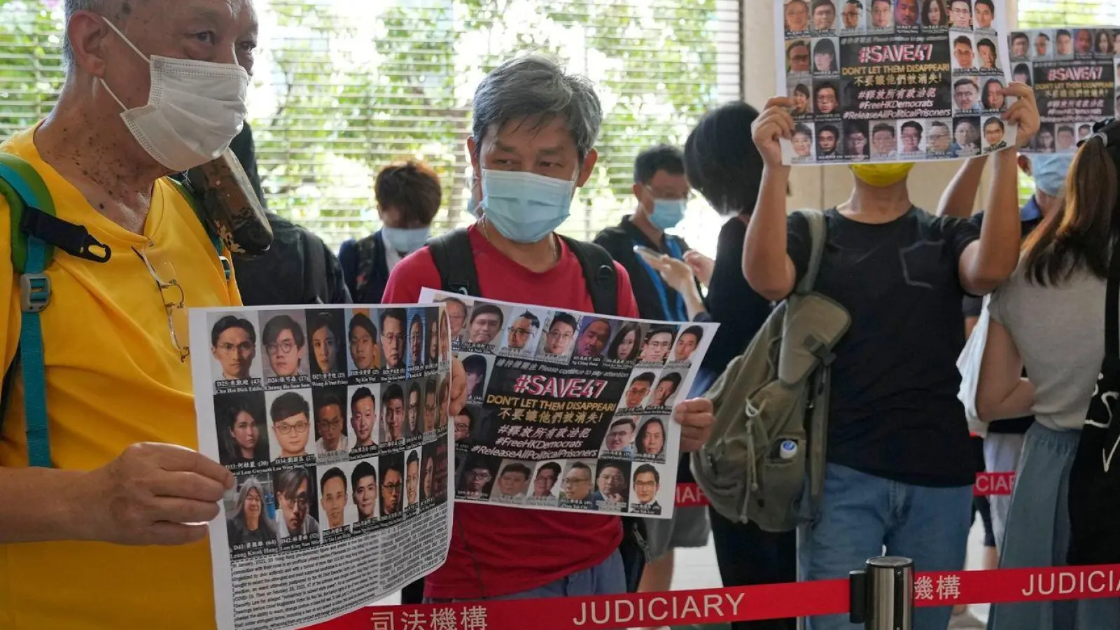 Unterstützer halten vor einem Gericht in Hongkong Plakate mit den Fotos einiger der 47 angeklagten Demokratie-Aktivisten in die Höhe. (Foto: Kin Cheung/AP/dpa)