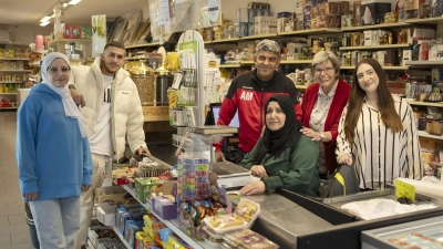 Mohamad Al Baradan (stehend mit Trainingsjacke), seine Frau Nahla Al Ribday (sitzend), ihre Kinder Sarah (links) und Noor (Zweiter von links) sowie Noors Ehefrau Leila (rechts) und Irmi Brenner (Zweite von rechts) im Laden der Familie in der Neustädter Parkstraße. (Foto: Andreas Riedel)