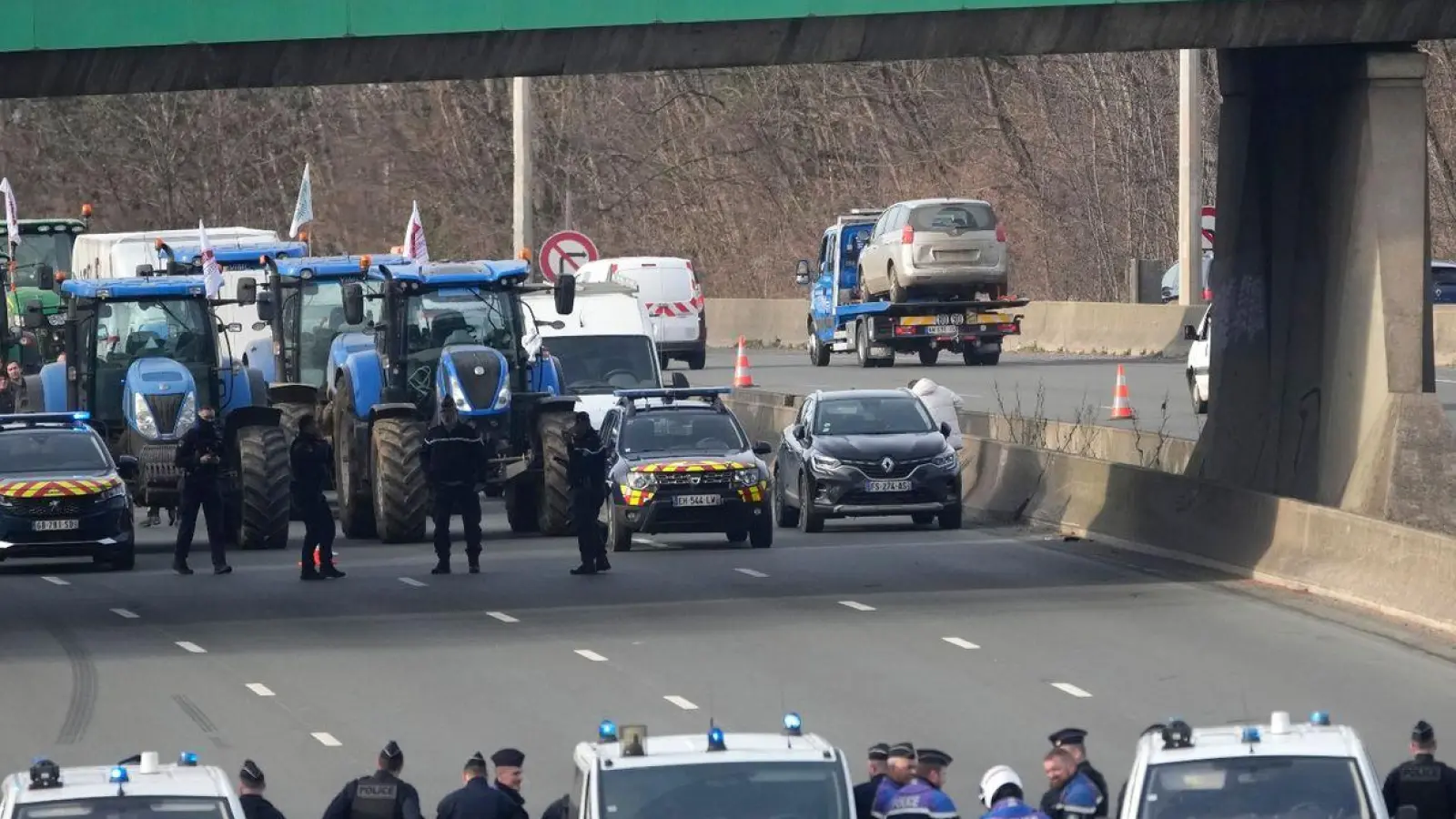 Bauern auf einer Autobahn bei Argenteuil. Mehrere Bauernverbände haben zu landesweiten Protesten gegen Löhne, Steuern und Vorschriften aufgerufen und kündigten an, Paris am Montag mit Traktorbarrikaden und Fahrverboten einzukreisen. (Foto: Christophe Ena/AP/dpa)