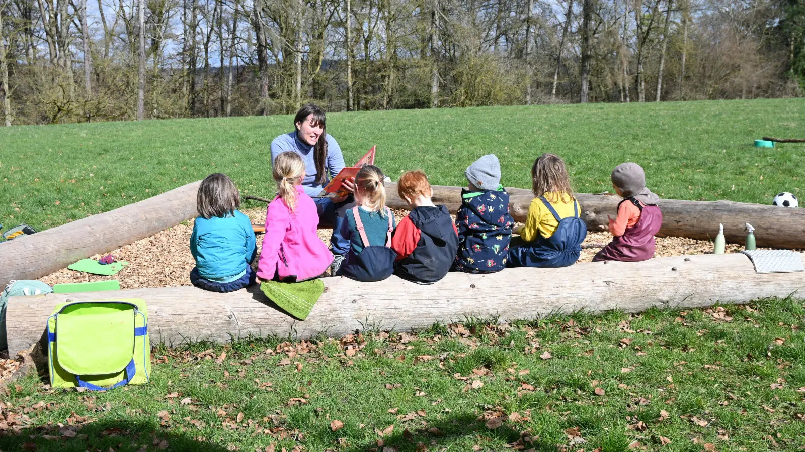 Derzeit werden elf Kinder betreut. Im Sitzkreis auf der großen Wiese lauschen sie gespannt der Mitarbeiterin Matrona Cheregi. (Foto: Luca Paul)