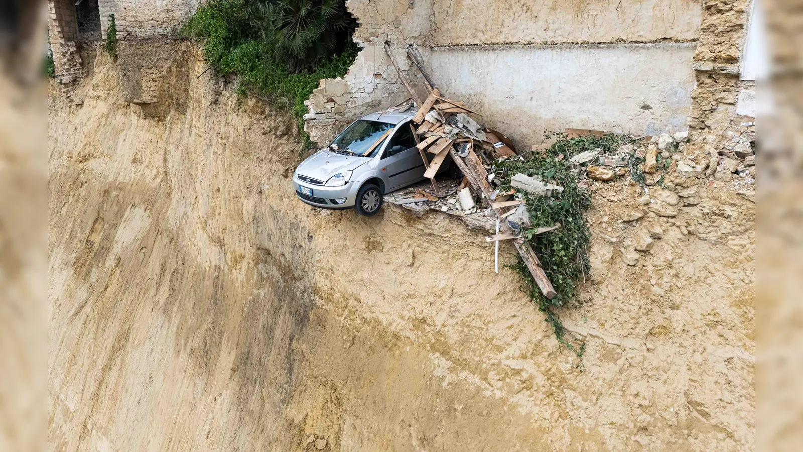 Nach dem schweren Erdrutsch auf Sizilien hängt ein Auto über einem Abgrund.  (Foto: Andrea Petrelli/IPA via ZUMA Press/dpa)
