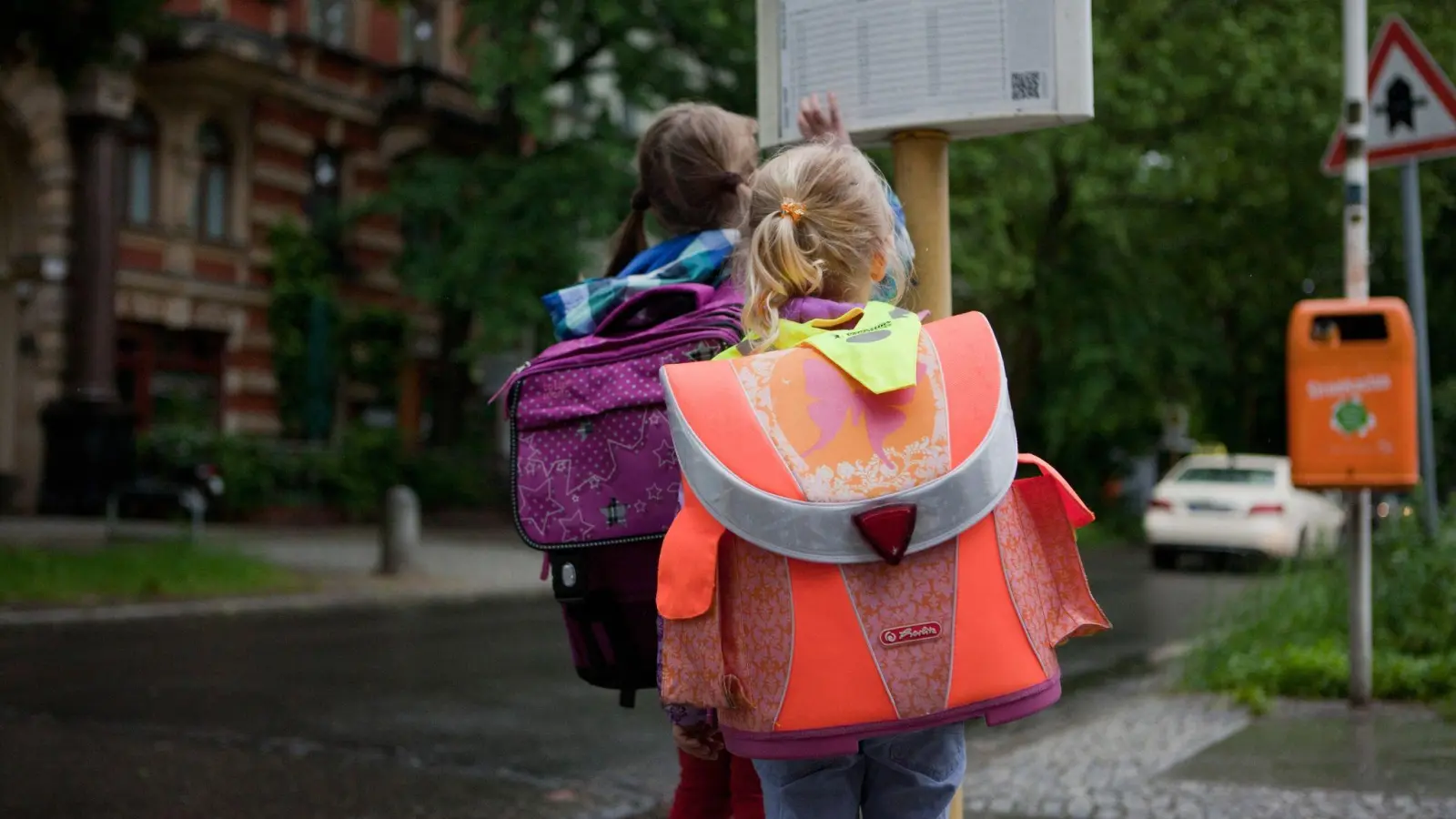 Schulkinder an der Bushaltestelle: Nicht immer lesen sie so ruhig den Fahrplan. Vor allem, wenn getobt wird, sollten Autofahrer Vorsicht walten lassen. (Foto: Silvia Marks/dpa-tmn)