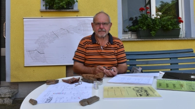 Günther Rabenstein, Obmann der Osing-Verwaltung und Hüter der Traditionen, bei sich zu Hause in der Modelsmühle: Versteinertes Holz vom Osing beschwert vor ihm das Papier. (Foto: Anita Dlugoß)