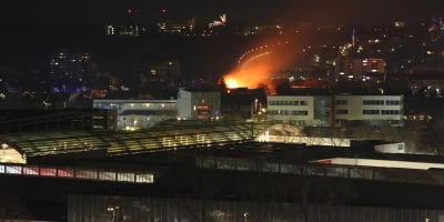 Weithin sichtbar sind die Flammen, die aus dem Wohnhaus schlagen, während nebenan mit Feuerwerkskörpern und Raketen der Beginn des Jahres 2026 gefeiert wird. (Foto: Alexander Biernoth)