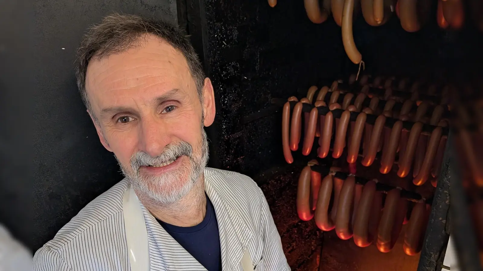 Metzgermeister Friedrich Menhorn kontrolliert das Buchenholzfeuer, über dem die Würste geräuchert werden. (Foto: Friedrich Zinnecker)