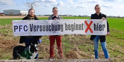 Sie fordern, dass endlich der PFC-Hotspot in der Katterbacher Kaserne angegangen wird (von links): André Fitzthum mit Hund Oskar, Wolfgang Schmidt und Boris-André Meyer von der Bürgerinitiative „Etz langt’s“. Im Hintergrund ist die Baustelle für die Abstromsicherung zu erahnen. (Foto: Alina Boger)