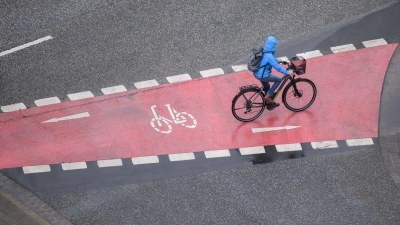 Eine Frau fährt bei Regen mit einem Fahrrad. (Foto: Julian Stratenschulte/dpa/Symbolbild)