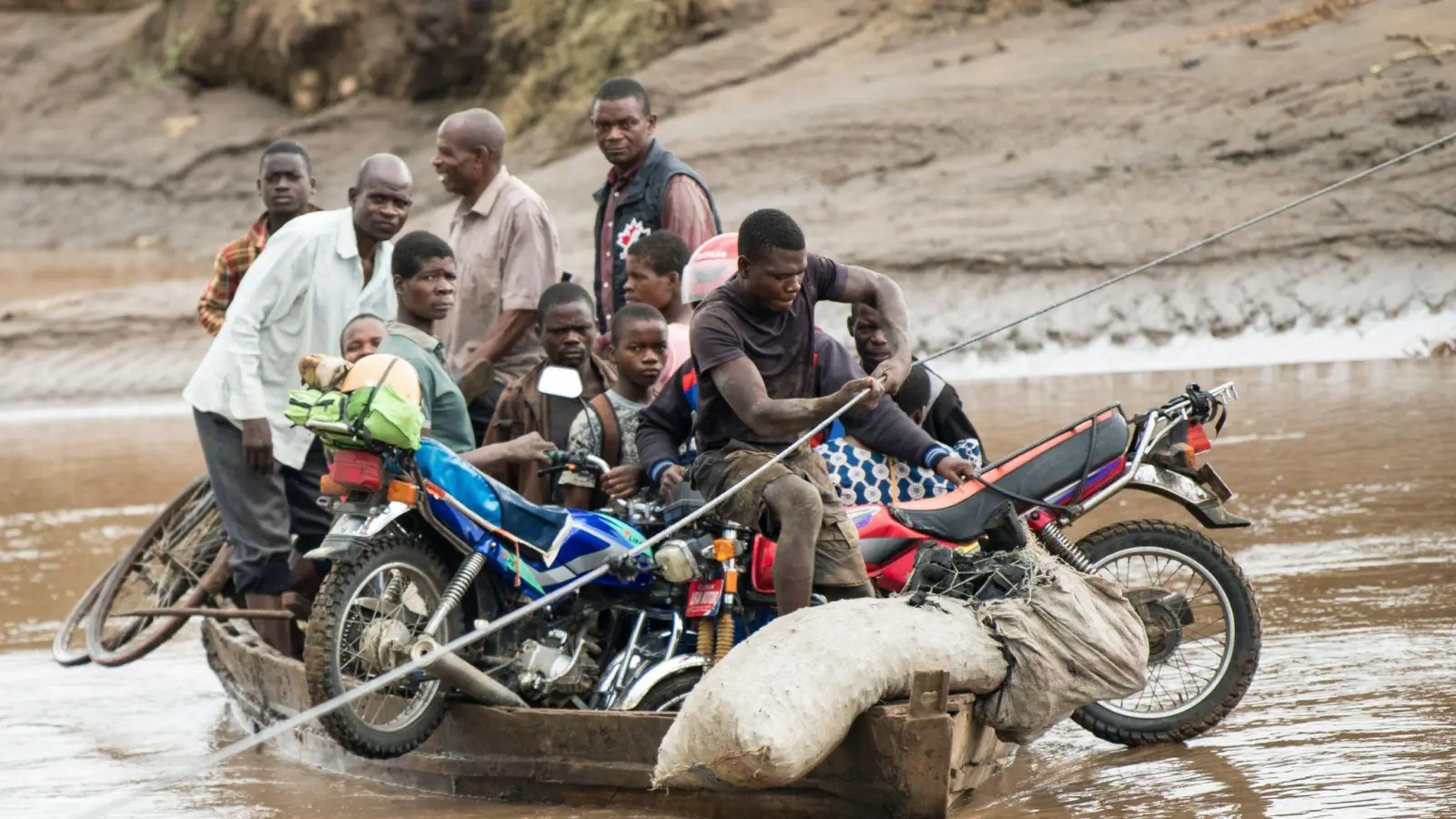 Männer transportieren in Malawi ihre geretteten Habseligkeiten mit einem Holzboot. (Foto: Thoko Chikondi/AP)