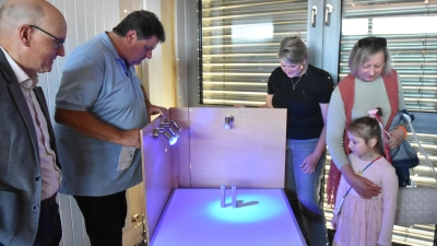 Schulverbandsvorsitzender Reinhard Seefried probiert die Schatten- und Farbwirkung bunter Lampen. Neugierig zeigten sich neben der kleinen Polina und ihrer Oma auch Uehlfelds stellvertretende Bürgermeisterin Carina Scherer (Mitte) und dem Vertriebsleiter der Raiffeisenbank Uehlfeld-Dachsbach, Volker Hofmann (links).  (Foto: Anita Dlugoß)