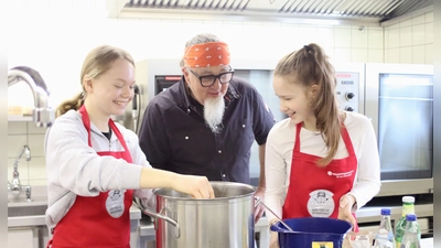 Sternekoch Stefan Marquard schaut den Schülerinnen über die Schulter: Marie Hauf und Vanessa Sindel (von links) bereiten die vegane und laktosefreie Soße auf Hafermilch-Basis für die Frikadellen zu. (Foto: Pauline Held)