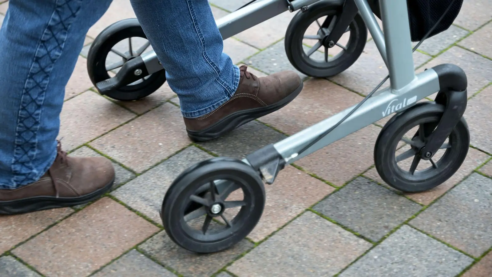 So geht's richtig: Die Füße befinden sich zwischen den Hinterrädern. Heißt: man geht nicht hinter, sondern im Rollator. (Foto: Michael Bahlo/dpa/dpa-tmn)