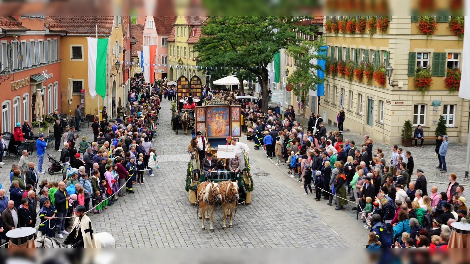 Farbenprächtiger Moment bei Mooswiesenfestzug auf dem Marktplatz: Die Zuschauerinnen und Zuschauer bewundern den Motivwagen „Wolgemuth – Meister des Feuchtwanger Marienaltars. (Foto: Kai Schlichtermann)