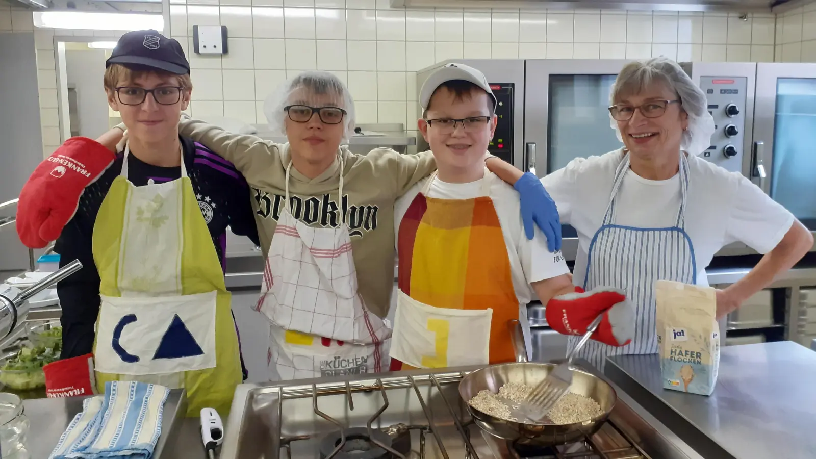 Clemens Weber, Linus Weick und Janne Mayer (von links) gehen Hauswirtschaftsmeisterin Erni Hübsch zur Hand und helfen in der Großküche der Edith-Stein-Realschule mit. (Foto: Marcus Pfalzer)
