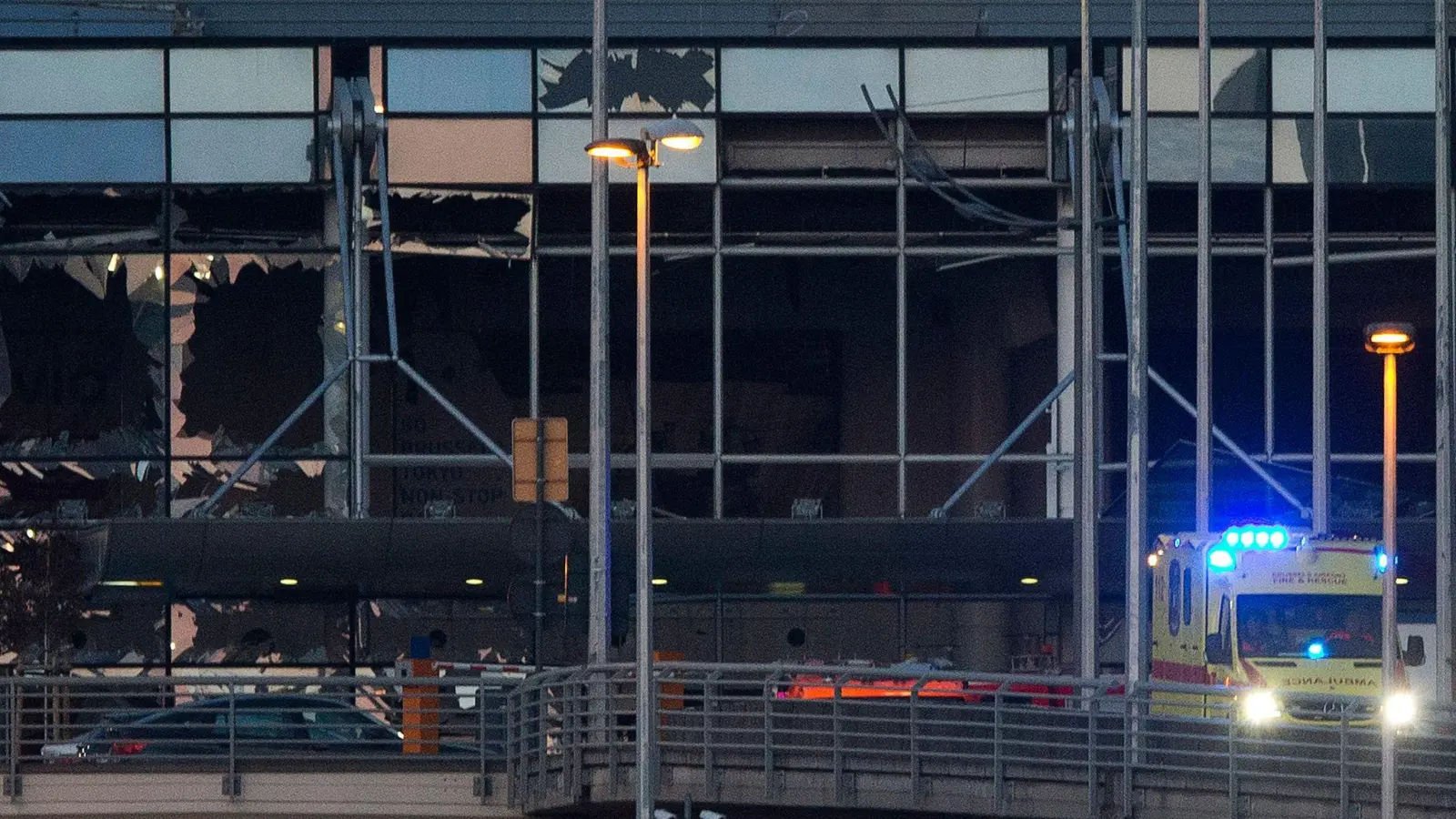 Ein Krankenwagen fährt an der zerstörten Fassade des Terminals des Flughafens Zaventem. (Archivbild) (Foto: Peter Dejong/AP/dpa)