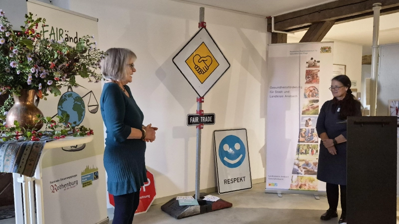 Christine Birmann von der Steuerungsgruppe Rothenburg (links) und Andrea Helmreich vom Landratsamt Ansbach, die die Schau zusammengestellt hat, enthüllten auch ein Verkehrsschild mit symbolischer Botschaft. (Foto: Margit Schwandt)