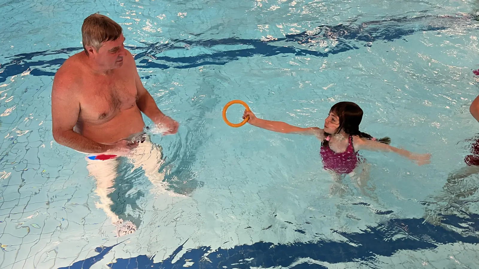 Die sechsjährige Clara übergibt Hannes Sommerer, dem Vorsitzenden der Wasserwacht Feuchtwangen, den Ring, den sie zuvor vom Beckenboden geholt hat. (Foto: Ann-Kathrin Wanger)