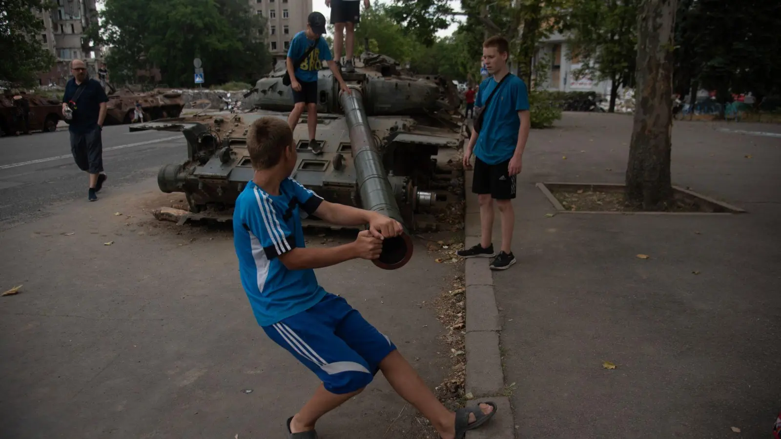 Jungen spielen an einem zerstörten russischen Panzer, der auf einer Straße von Mykolajiw steht. (Foto: Hector Adolfo Quintanar Perez/ZUMA Press Wire/dpa)