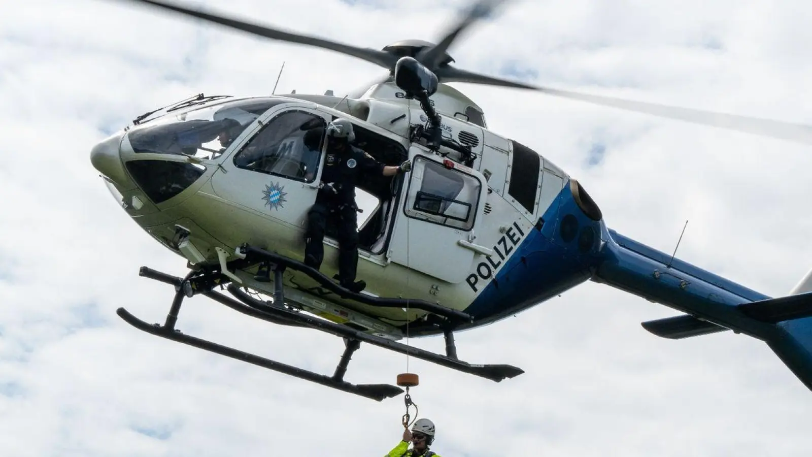 Ein Polizeihubschrauber zeigt während einer Luftrettungs-Übung an der Kampenwand das Abseilen einer Person. (Foto: Peter Kneffel/dpa)