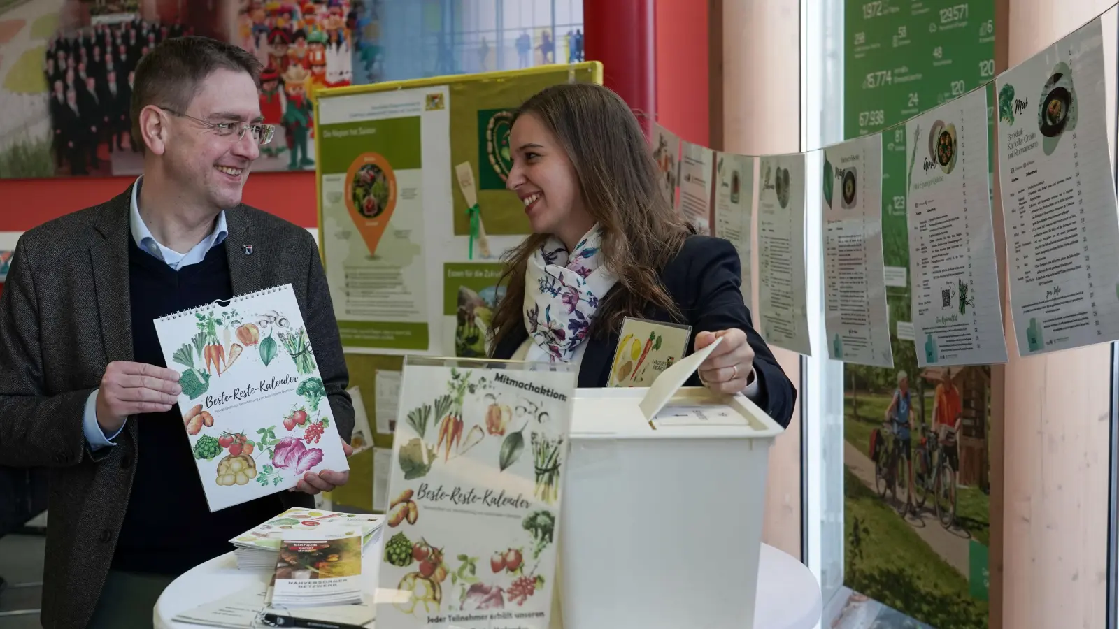 Gemeinsam für weniger Lebensmittelabfälle: Landrat Jürgen Ludwig und Lena Navarro Ortiz zeigen die „Beste-Reste“-Ausstellung und den neuen Kalender im Landratsamt Ansbach. (Foto: Landratsamt Ansbach/Fabian Hähnlein)