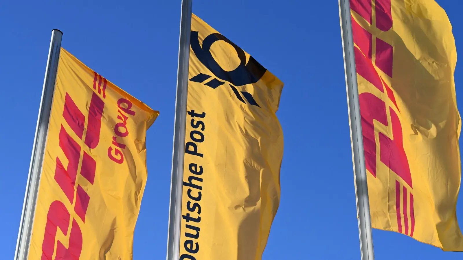 Eine Deutsche-Post-Fahne an der Konzernzentrale umrahmt von DHL-Fahnen. So soll es bleiben. (Foto: Wolf von Dewitz/dpa)