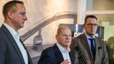 Betriebsratschef Benjamin Gruschka (l) neben Bundeskanzler Olaf Scholz (SPD) und Marcus Wassenberg (r), Geschäftsführer der Ford-Werke. (Foto: Christoph Reichwein/dpa)