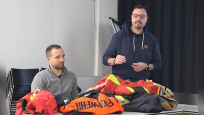 Feuerwehrkommandant Patrick Noll (stehend) hatte verschiedene Modelle mitgebracht, damit die Stadträte ein Bild davon haben, was die Unterschiede der Feuerwehrjacken und -hosen sind. Kämmerer Heiko Wittig ist in der Verwaltung für das Feuerwehrwesen zuständig. (Foto: Robert Maurer)