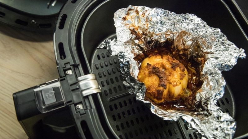 Keine gute Idee: Durch die Alufolie im Airfryer kann die Luftzirkulation gestört werden - die Lebensmittel werden so weniger knusprig. (Foto: Christin Klose/dpa-tmn)