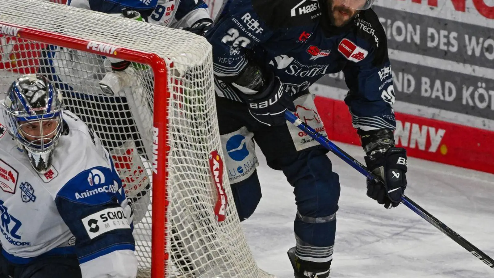 Justin Scott (r) von den Straubing Tigers versucht, den Puck ins Tor von Joacim Eriksson von den Schwenninger Wild Wings zu bekommen. Scott verlängert seinen Vertrag in Straubing. (Foto: Armin Weigel/dpa)