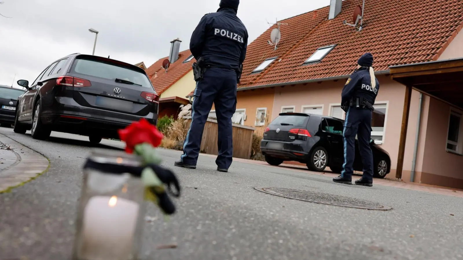 Polizisten stehen neben einer Trauerkerze vor einem Haus. Eine Gewalttat hat den 6800-Einwohner-Ort Weisendorf erschüttert.  (Foto: Daniel Löb)