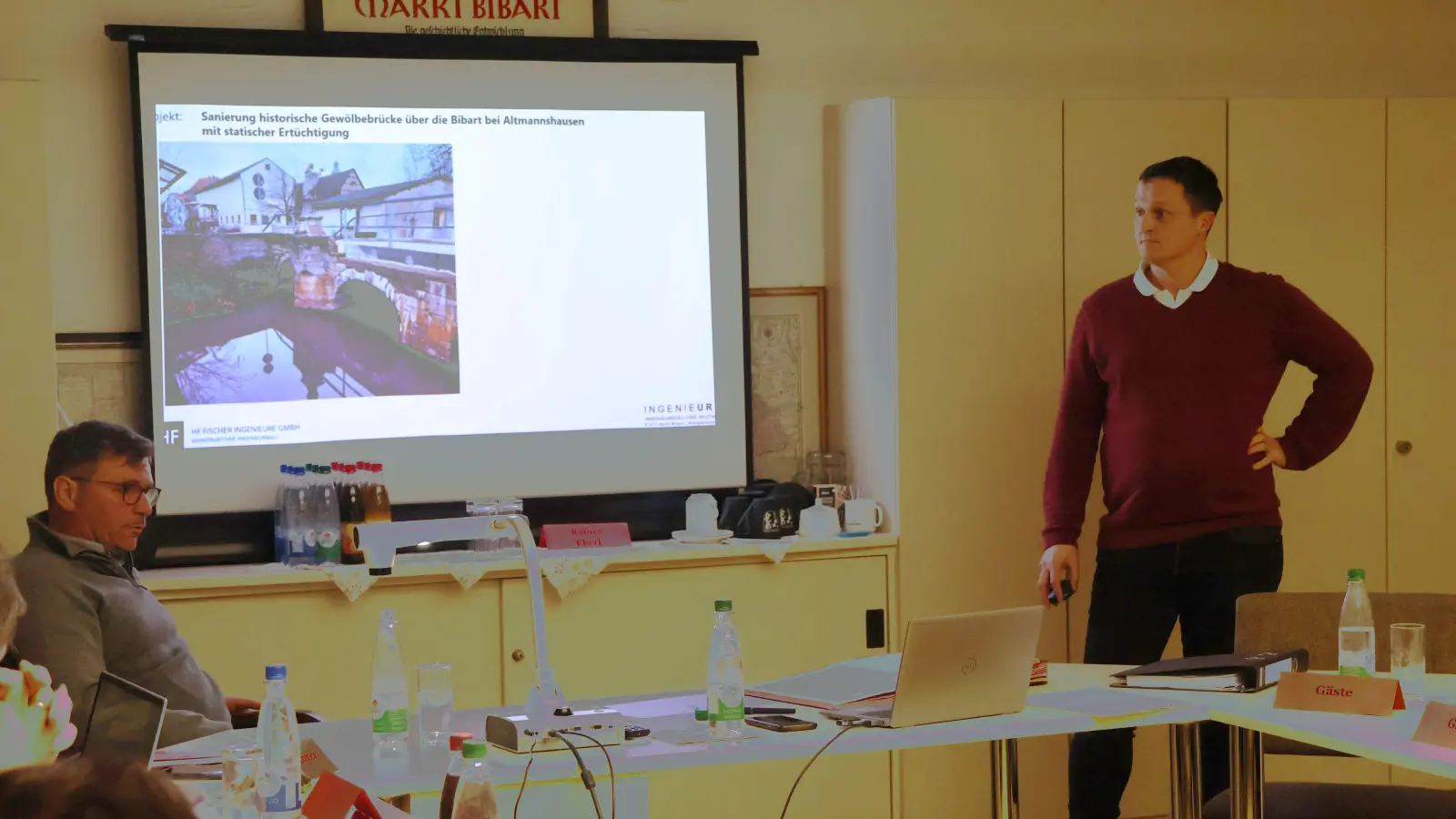 Ingenieur Uwe Reuther (stehend) erläuterte dem Markt Bibarter Ratsgremium den Sachstand zur Wiederherstellung der Altmannshäuser Brücke. Im Frühsommer soll die Sanierung beginnen. (Foto: Andreas Reum)