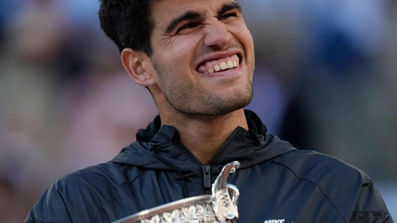 Carlos Alcaraz feiert mit der Trophäe nach seinem Sieg. (Foto: Thibault Camus/AP)