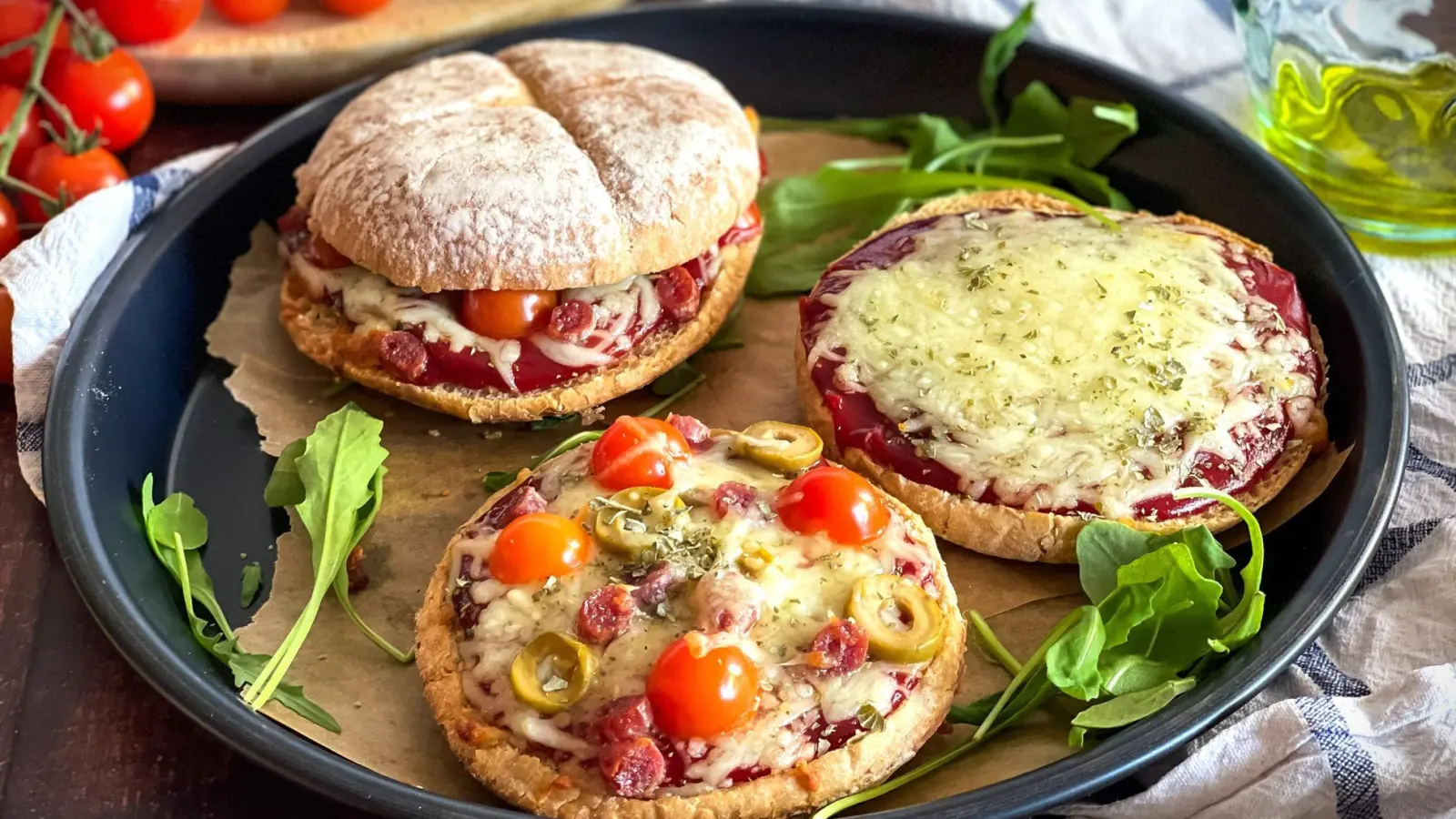 Ein rustikales Hamburgerbrötchen wird zur Pizzabasis, belegt mit Tomatenketchup, geschmolzenem Mozzarella und mediterranen Zutaten. (Foto: Anja Würfl/die-frau-am-grill.de/dpa-tmn)