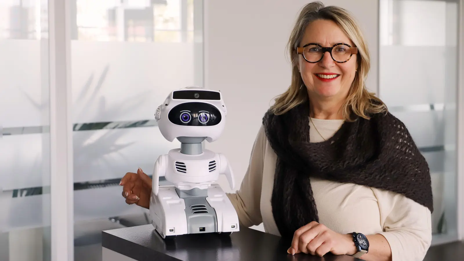 Die Leiterin der IHK-Geschäftsstelle Ansbach, Karin Bucher, zeigt Mia. Der drollige kleine Roboter der Kammer soll es ein wenig lenken, junge Menschen mit Blick aufs Thema Ausbildung zu beraten. (Foto: Oliver Herbst)