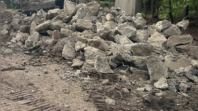 Große Betonteile lagern derzeit auf der Petersauracher Seite der ehemaligen Brücke. Ein Spezialunternehmen ist gerade dabei, die tonnenschweren Stücke zu zerkleinern. (Foto: Florian Pöhlmann)