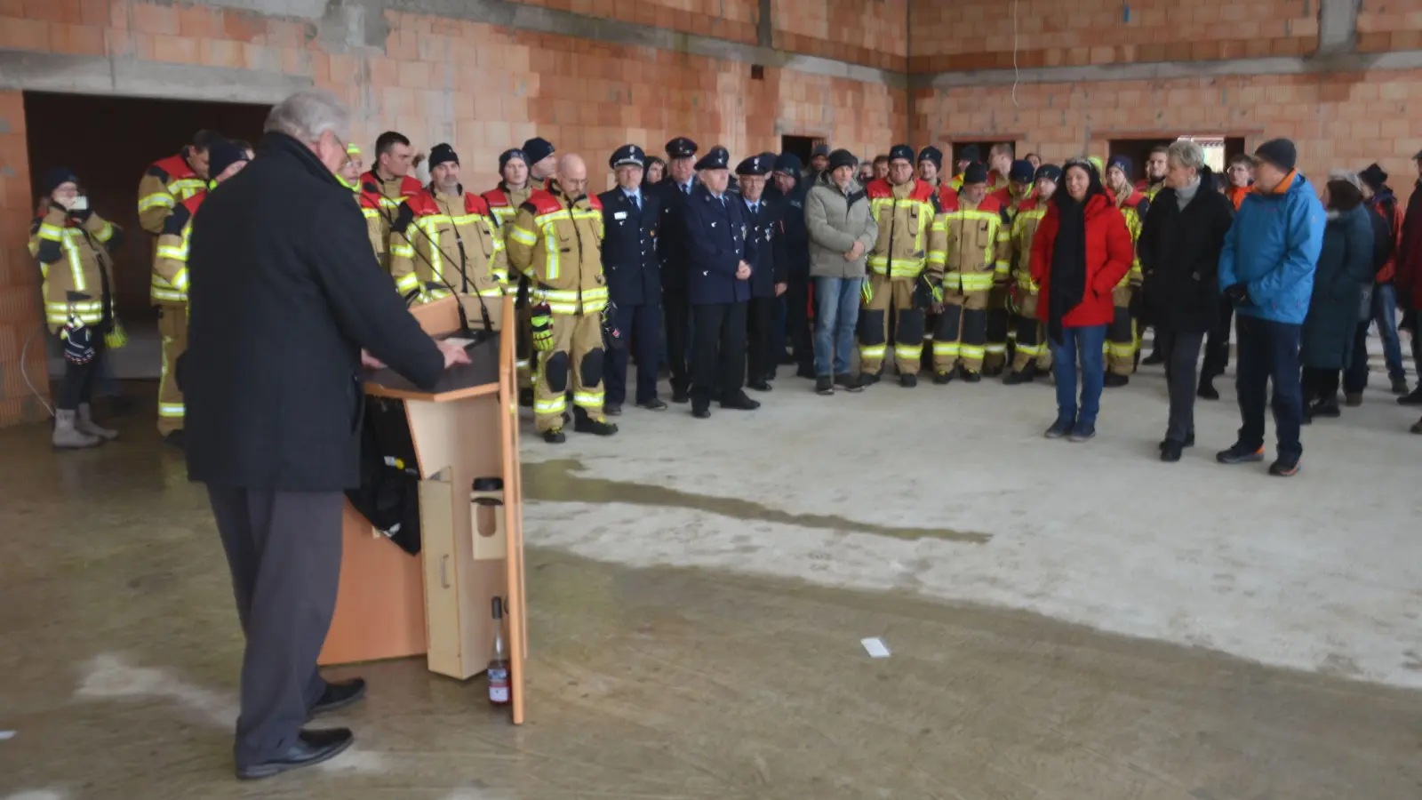 Stadträte, Mitarbeiter der Verwaltung und der beteiligten Baufirmen, Nachbarn und vor allem eine stattliche Anzahl von Feuerwehrleuten waren zum Richtfest gekommen und lauschten unter anderem der Ansprache von Bürgermeister Klaus Meier (vorne). (Foto: Patrick Lauer)