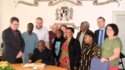 District Pastor Gervas Meitamei inmitten seiner Delegation und umgeben von Mitgliedern des Uffenheimer Dekanats und Bürgermeister Wolfgang Lampe (links) beim Eintrag ins Goldene Buch der Stadt. (Foto: Gerhard Krämer)