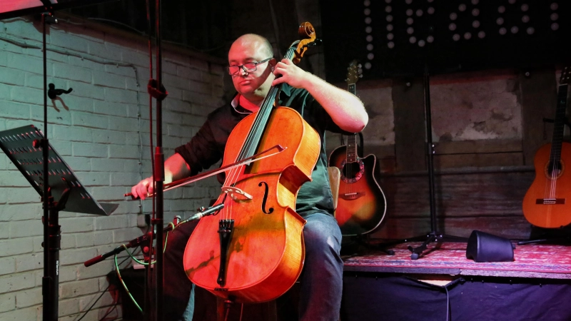 Greift zwischen seinen Gitarrenliedern gern zum Cello: Karl Henniger beim Konzert in der Kunstmühle Flachslanden. (Foto: Martina Kramer)