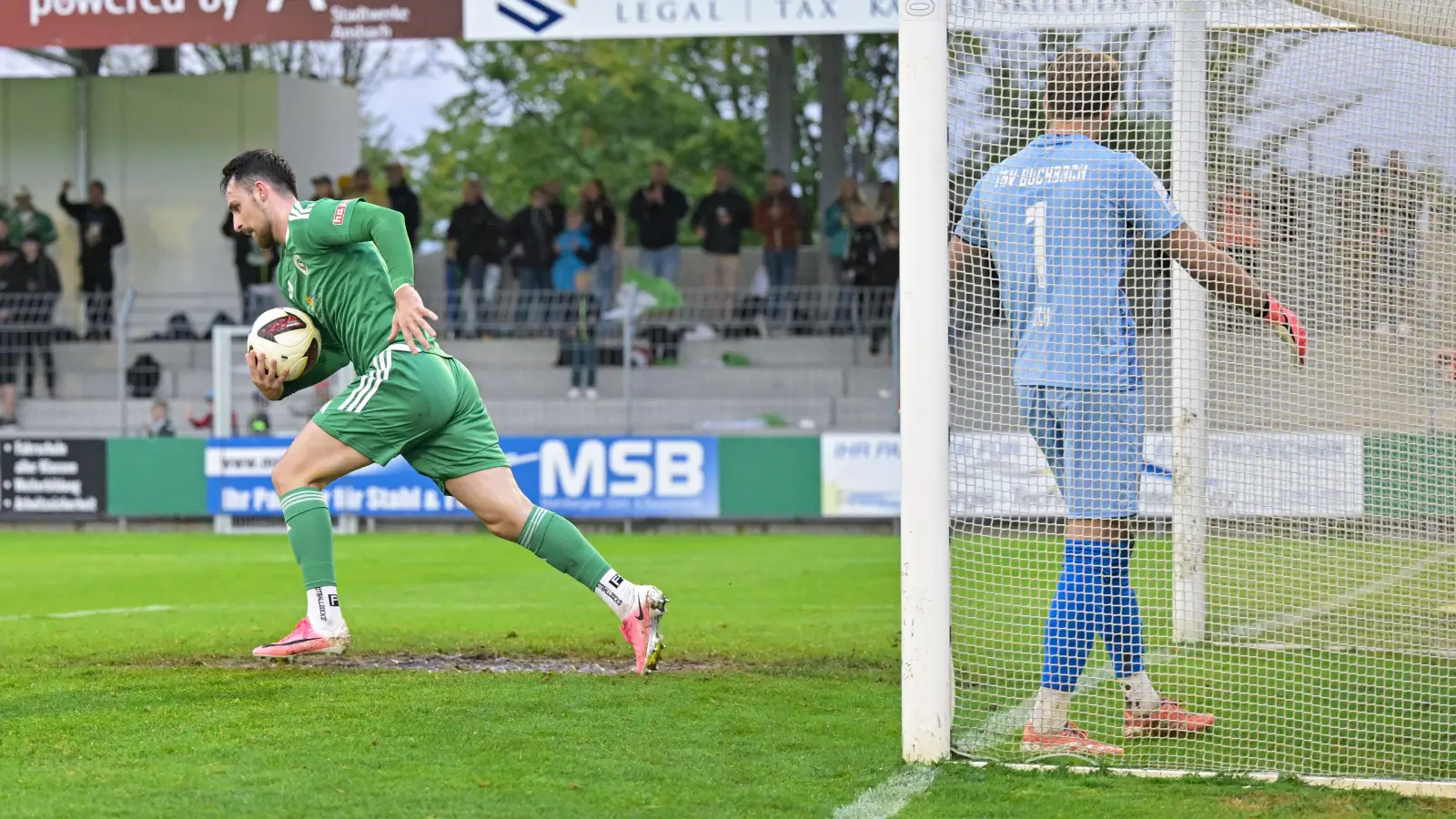 Jetzt aber schnell: Der Ansbacher Dino Nuhanovic trägt nach seinem Tor zum 1:3 den Ball zum Anstoß. Rechts der Buchbacher Torwart Ludwig Zech. (Foto: Martin Rügner)