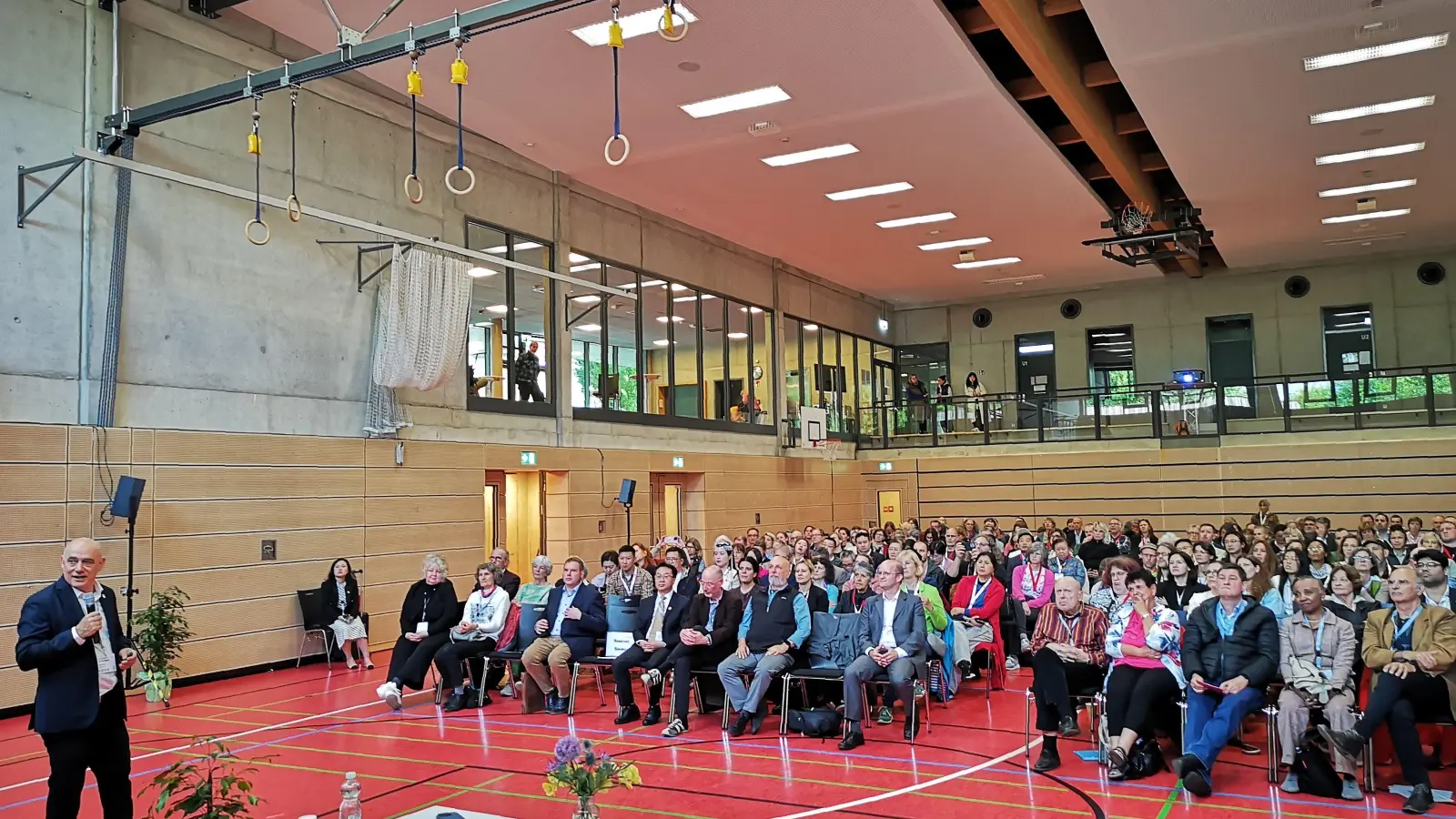Wo normalerweise Sportveranstaltungen stattfinden, wurde der Kongress eröffnet. Das Foto entstand beim Vortrag von Dr. Yair Mamon aus Israel, Präsident der Europäischen TCM-Dachorganisation (links). (Foto: Jürgen Binder)