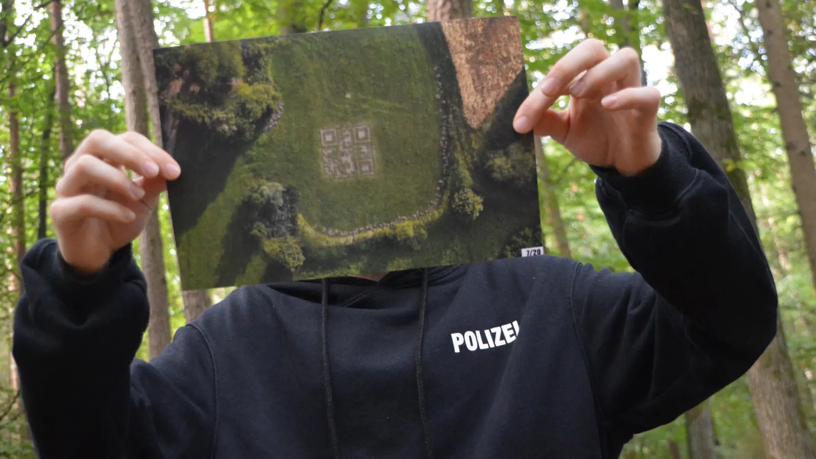 Damit „Ra.g.e.“ unerkannt bleibt, hält er sich ein Drohnenfoto seines QR-Codes vors Gesicht. (Foto: Johannes Zimmermann)