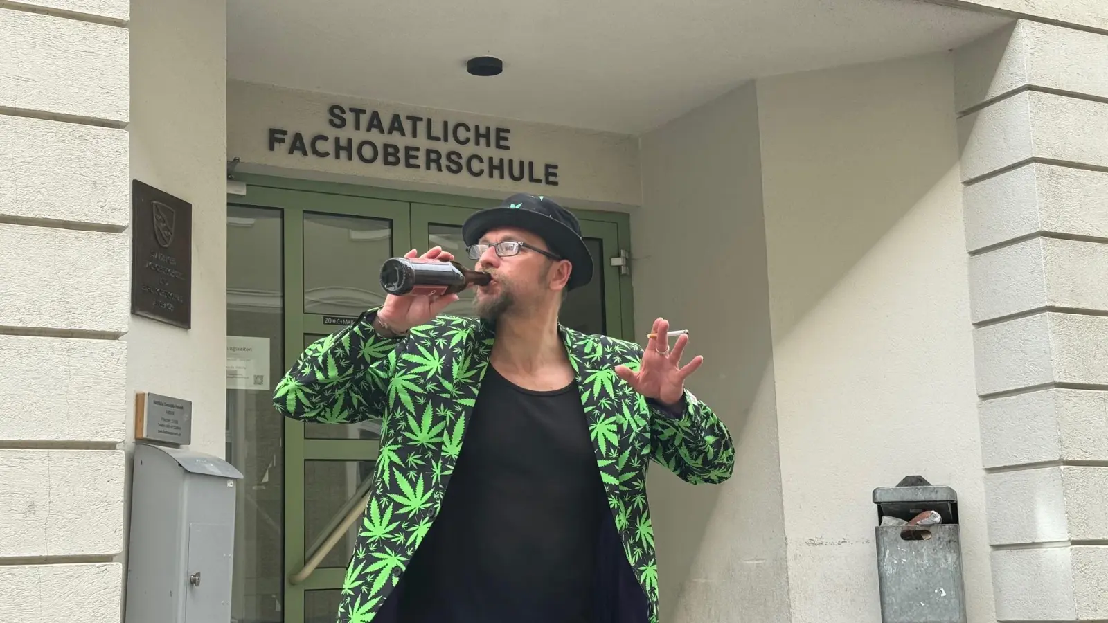 Michael Jakob posiert derzeit täglich im Hanfblatt-Anzug und mit Bierflasche und Zigarette vor bayerischen Schulen für Fotos. Mit dieser Aktion möchte der Poetry-Slammer auf den unterschiedlichen Umgang Bayerns mit Cannabis sowie Alkohol und Nikotin hinweisen. (Foto: Lara Hausleitner)