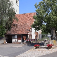 Ein Bauzaun sichert einen Bereich vor dem alten Feuerwehrgerätehaus in Altmannshausen. An der Ecke, an der bereits Mauerwerk herausgefallen ist, wurde eine lebensgroße Puppe mit Warnkleidung ins Gebäude gestellt. (Foto: Andreas Reum)