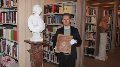 Christian Mantsch, der Leiter der Staatlichen Bibliothek Ansbach, zeigt neben der neuen Büste von Markgraf Carl Wilhelm Friedrich den Fundationsbrief. (Foto: Robert Maurer)
