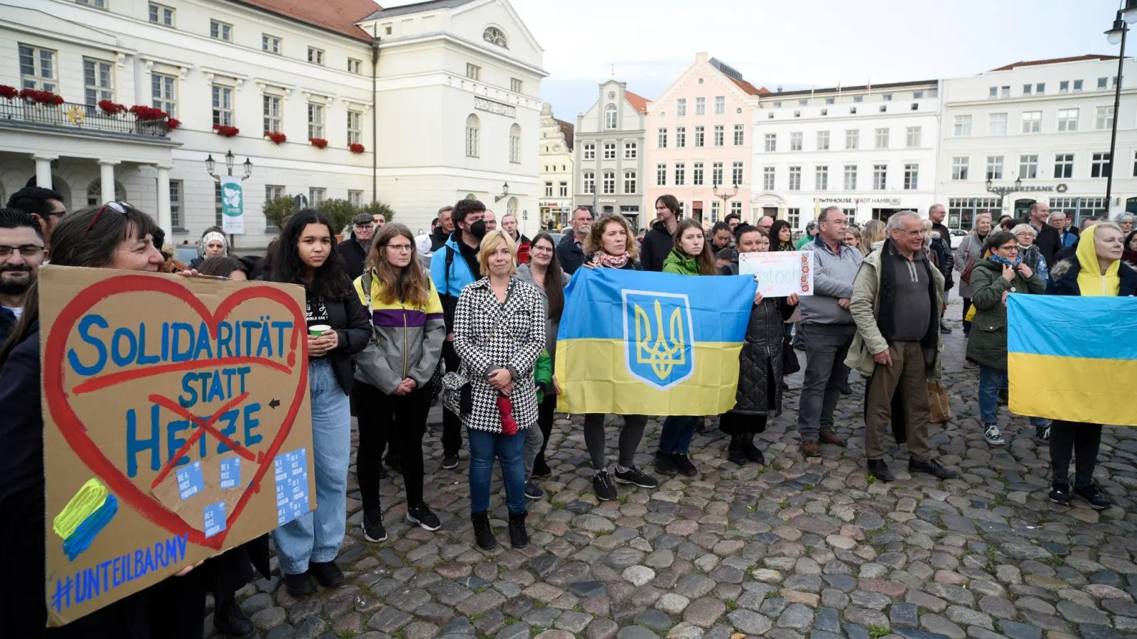 Ukrainische Frauen und weitere Teilnehmer stehen bei einer Mahnwache auf dem Wismarer Marktplatz. (Foto: Frank Hormann/dpa)