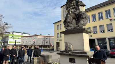 Der Luitpoldbrunnen wurde von den Bomben zerstört, nun erinnern die zusammengefügten Bruchstücke an den Krieg: Oberbürgermeister Thomas Deffner (rechts) las bei der Gedenkstunde vor, was sein Vater am 22. Februar 1945 erlebt und später niedergeschrieben hat. (Foto: Lara Hausleitner)